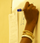 Student's hand writing on a white board